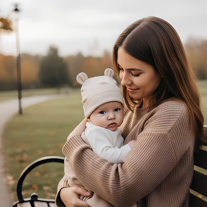 bonnet bebe clair oreilles ourson bebe bras adulte banc parc automne ambiance chaleureuse